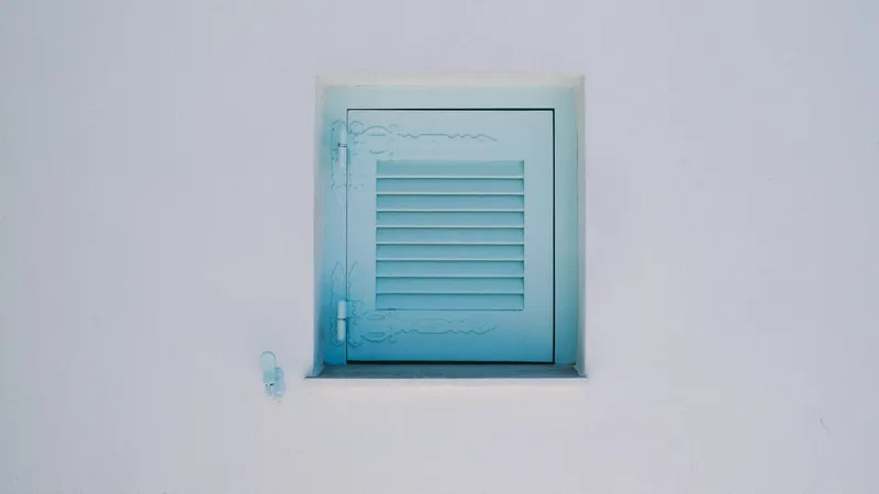 Pared blanca con una pequeña contraventana de madera azul cerrada