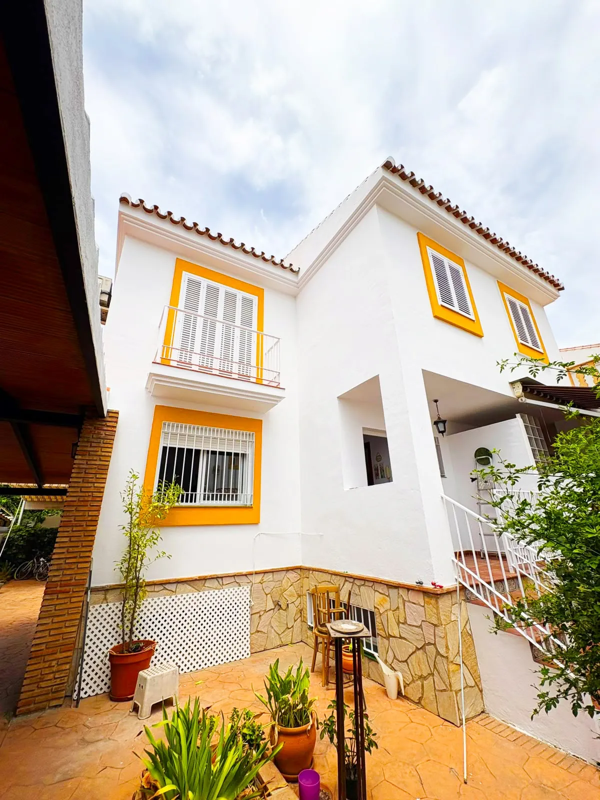 Fachada de dos plantas en blanco, con los recercados de las ventanas en mostaza