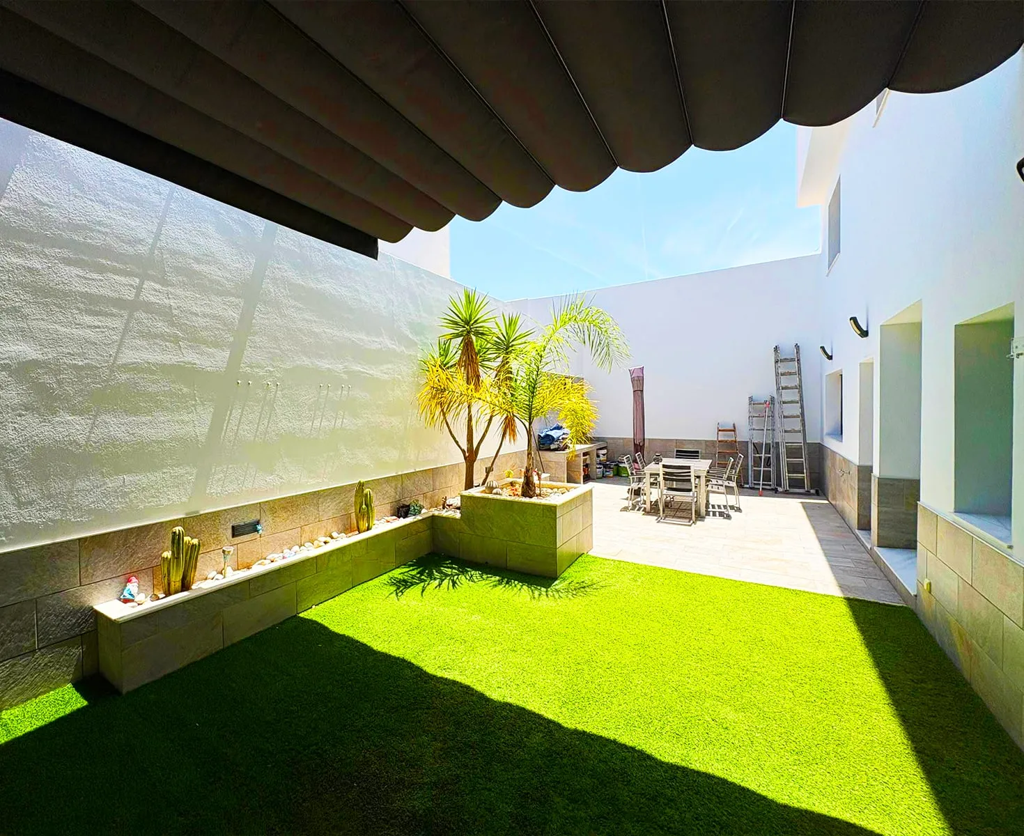 Muros del patio pintados en blanco en una vivienda con jardín