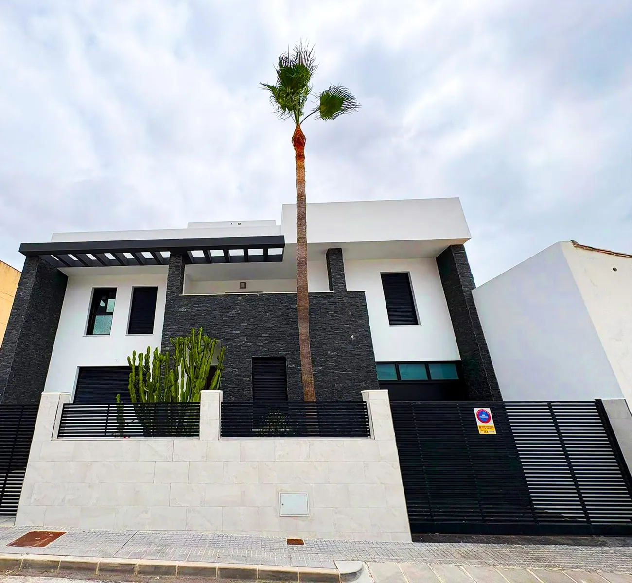 Obra real de VARELUX: villa moderna con la fachada pintada en blanco junto a la piedra oscura